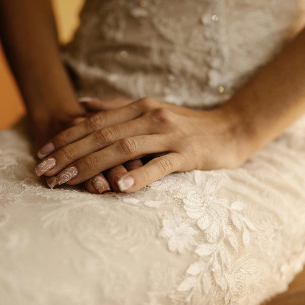 Mani curate con smalto nude su abito da sposa in pizzo